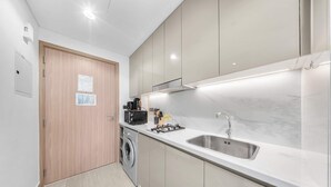 Una cucina moderna con lavatrice integrata, un lavello e un piano cottura.