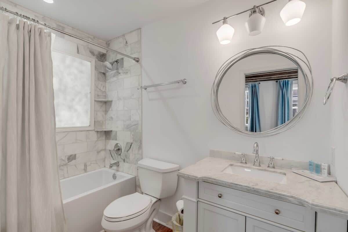 Een moderne badkamer met een douche van marmer, een toilet, een wastafel met spiegel en een badkamermeubel.