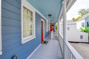 A covered porch with a red door, white railings, and a blue exterior wall.