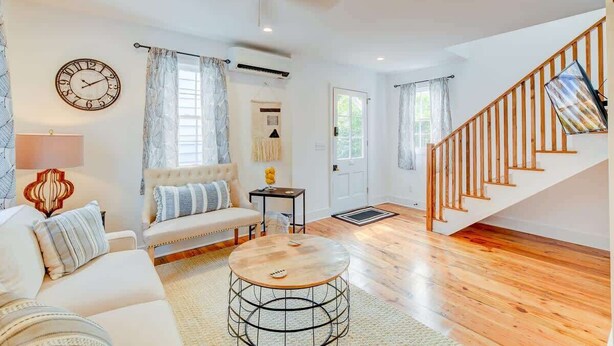 A spacious living room with a wooden staircase, a round coffee table, and a sofa. - Cottage with Privacy, 150ft to King + Parking (Charleston)
