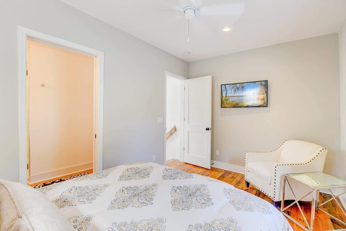 A bedroom with a bed, a chair, and a painting on the wall.
