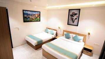A hotel room with two beds, a nightstand, a wall-mounted light, and two framed pictures.