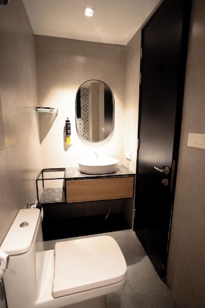 Een moderne badkamer met een wit toilet, een ronde spiegel en een wastafel met een zwart aanrecht.