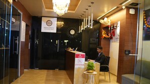A reception desk with a sign for 'Gentlemen's Lounge Bar,' a clock, and a modern chandelier. - Everest Inn Chakan (Chakan)