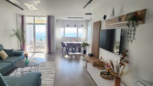 Een moderne woonkamer met een bank, salontafel en een eethoek met stoelen.