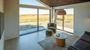 Un intérieur moderne avec de grandes portes vitrées, une table ronde en bois et un canapé gris.