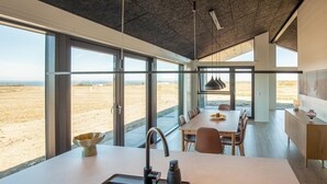 Une cuisine moderne dotée d’un grand îlot central, d’un coin repas offrant une vue agréable et d’un design minimaliste.