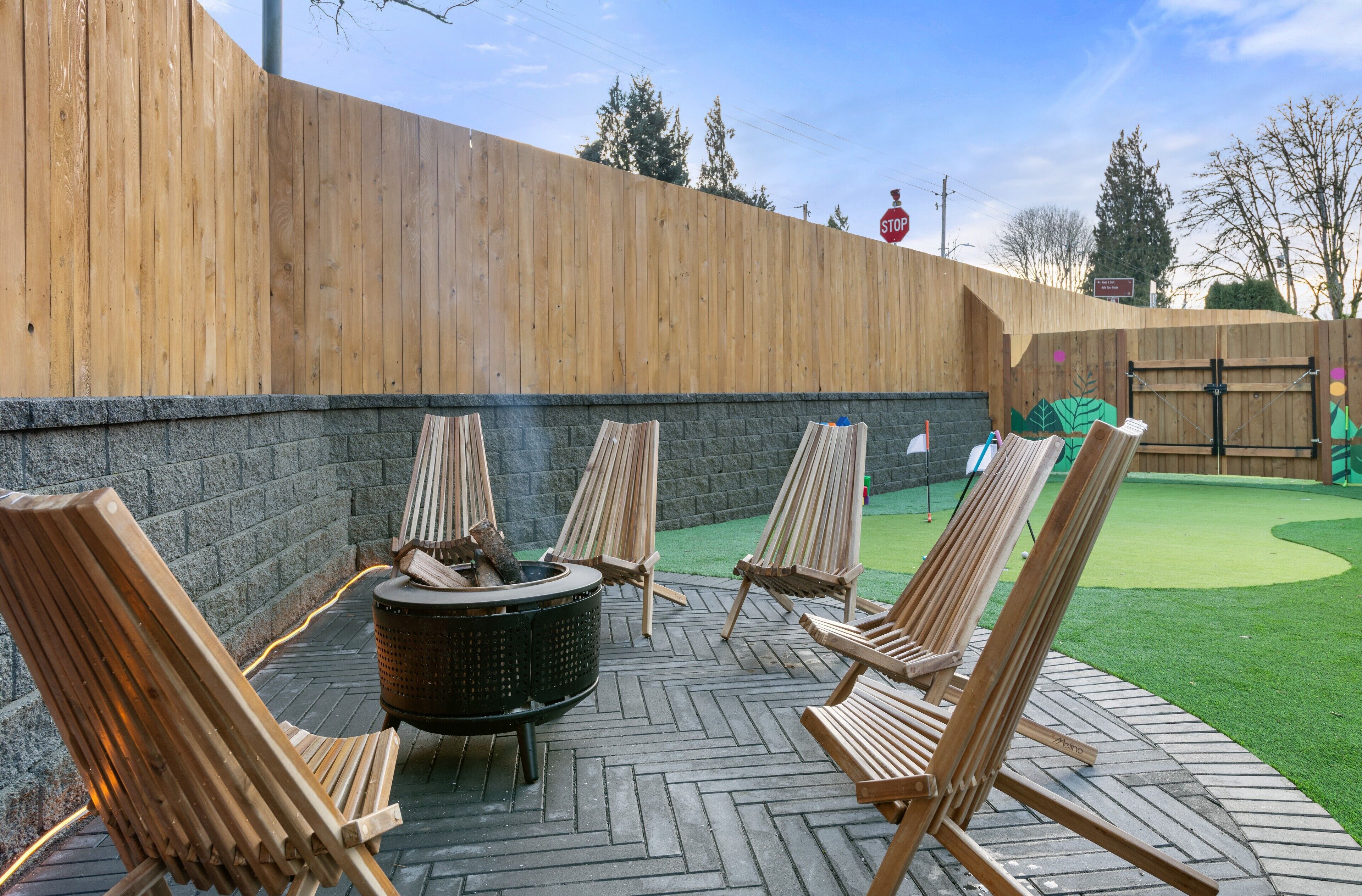Ein Patio mit Holzstühlen und einem Feuerkorb.