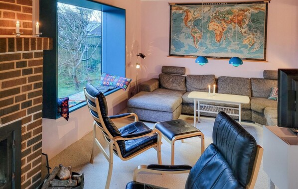 Un salon chaleureux avec une cheminée, un ensemble de canapés, une table basse et une carte du monde accrochée au mur.