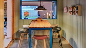 Una cucina con un tavolo di legno, sgabelli, un mappamondo e una finestra che si affaccia su un giardino.