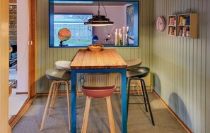 Une cuisine avec une table en bois, des tabourets, un globe terrestre et une fenêtre donnant sur un jardin.