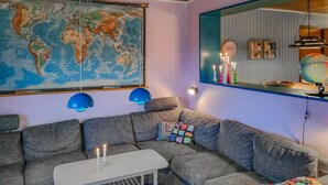 Un soggiorno accogliente con una grande mappa del mondo, un divano grigio, un piccolo tavolino bianco e un globo su uno scaffale.