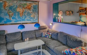 Un salon chaleureux avec une grande carte du monde, un canapé gris, une petite table blanche et un globe posé sur une étagère.
