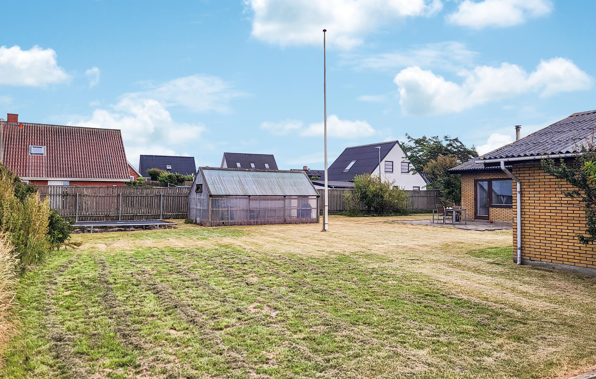 Ein Wohngrundstück mit Rasen, Holzzaun und Metallschuppen.
