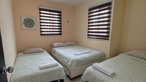 A room with three beds, a ceiling fan, and two windows with blinds. - Casa Villas Amanecer only 5 minutes away from Merida's periferico (Kanasín)