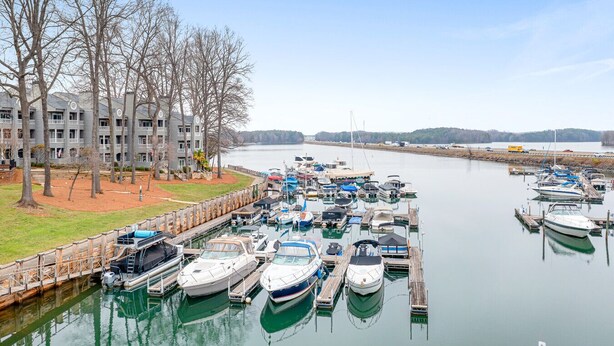 A marina with various boats docked, a building with balconies, and a clear sky. - Sunrise Cove on Lake Norman (Davidson)