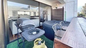 Un balcón con una parrilla, una zona de estar techada y vistas al interior del edificio.