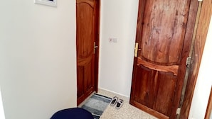 Ein Flur mit einer Holztür, einem gerahmten Bild an der Wand und einem blauen Pouf auf dem Boden.