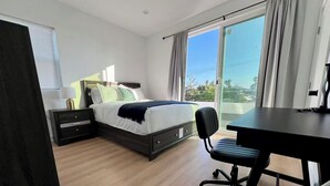 Un dormitorio moderno con cama, mesitas de noche, un escritorio y una silla.