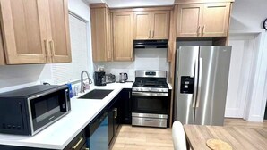 Una cocina moderna con armarios de madera, electrodomésticos de acero inoxidable y una encimera blanca.