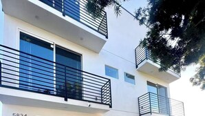 Un edificio residencial moderno de dos pisos con buzones numerados, un camino de entrada de grava y una pequeña área ajardinada.