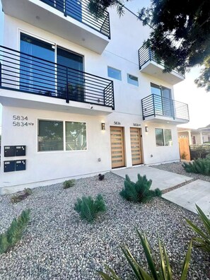 A modern two-story residential building with numbered mailboxes, a gravel driveway, and a small garden area. - Urban Pulse:4b4b 15 min to Sofi Stadium, DTLA, LAX and the Beach (Culver City)