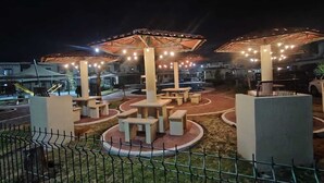 Un espace extérieur aménagé avec des tables et des bancs, entouré d’une clôture.