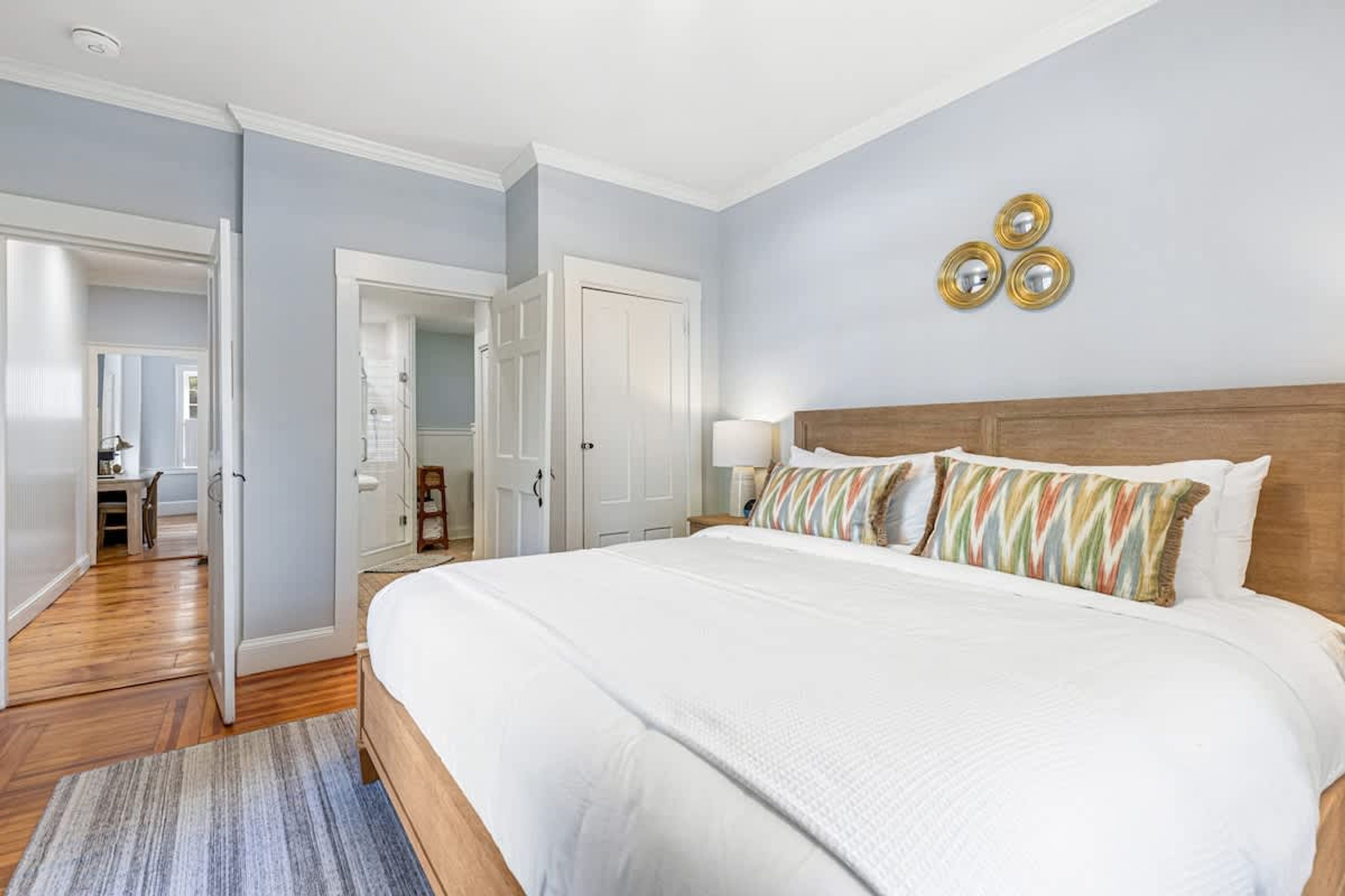 A bedroom with a large bed, a wooden headboard, and a nightstand with a lamp.