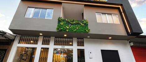 Ein modernes Hotel mit flachem Dach, einer Schilder mit der Aufschrift "Hotel Montaner Home" und einem Empfangsbereich mit Glastür und Fenstern.