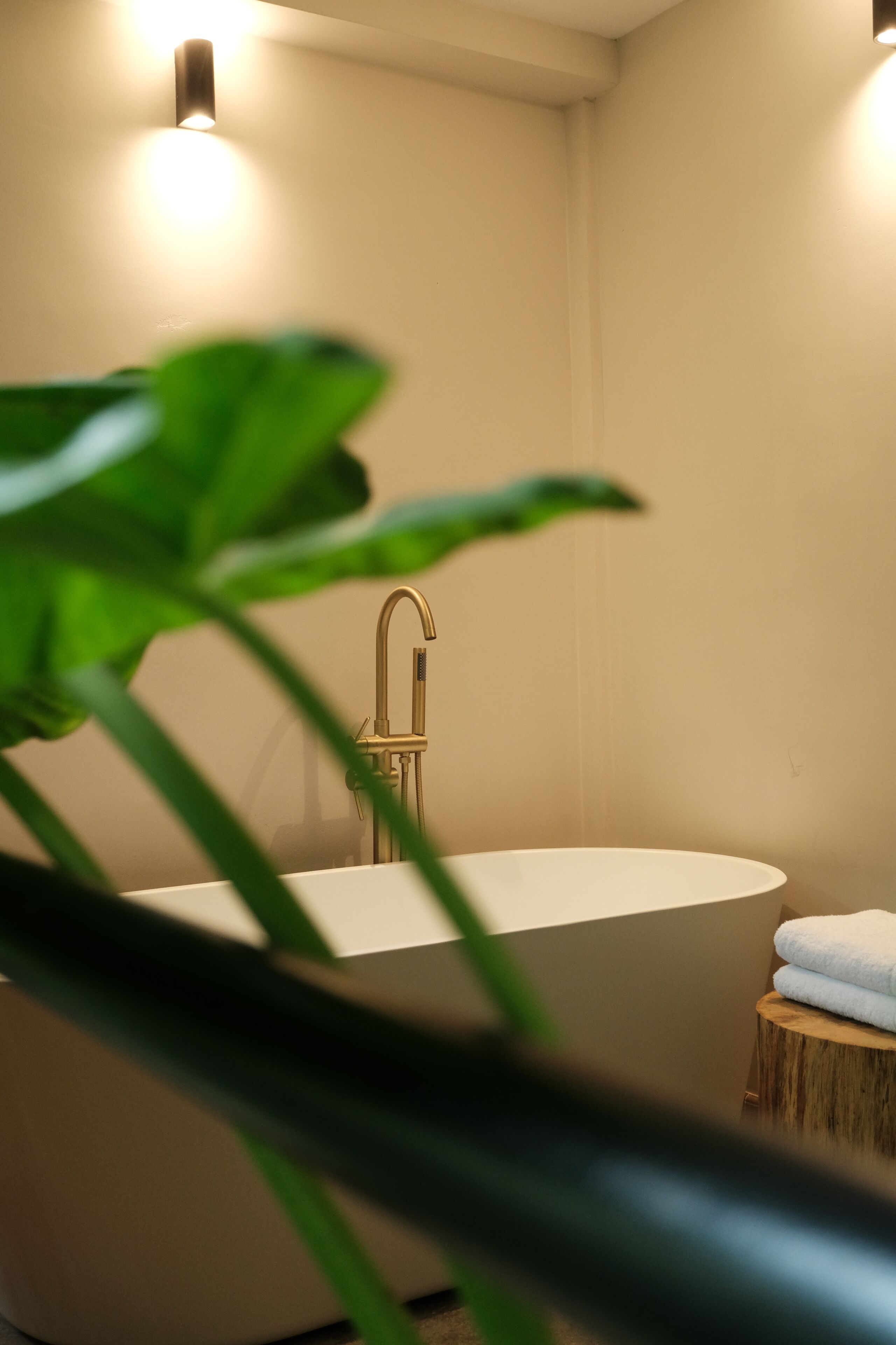 A bathroom with a freestanding bathtub, a wooden stool, and a towel.
