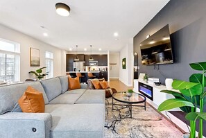 A modern living room with a sectional sofa, a coffee table, and a TV mounted on the wall.