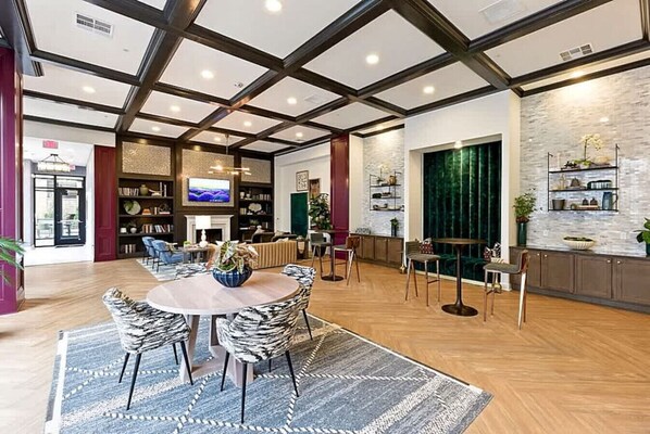 A spacious living area with a round wooden table, striped chairs, a fireplace, a television, and a bookshelf.