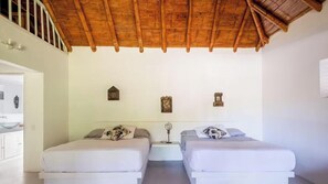 Ein Schlafzimmer mit zwei Betten, einer Holzbalkendecke und einer weißen Wand mit drei kleinen Wanddekorationen.