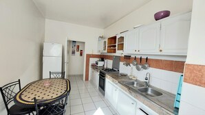 A compact kitchen with white cabinets, a gas stove, a sink, and a dining table with chairs. - Bright apartment with unobstructed view in the city center (Agadir)
