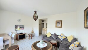 Ein Wohnzimmer mit einer Couch, einem Couchtisch, einem Fernseher und einem Essbereich mit Stühlen.