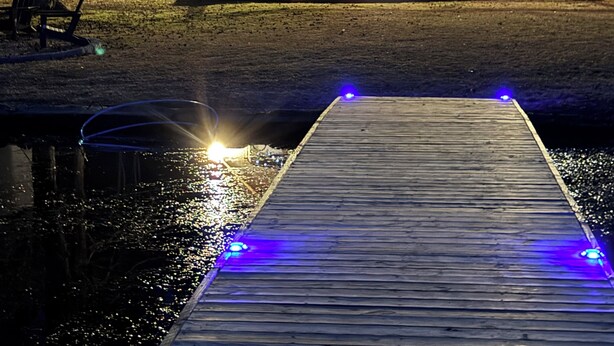 Una baita con una terrazza, un'area salotto esterna coperta e un molo che si protende sull'acqua.