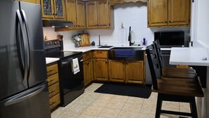 Una cucina con mobili in legno, un frigorifero nero, un fornello e un forno a microonde.