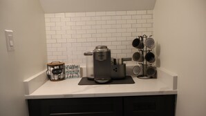 Una cucina con una macchina da caffè, un espositore per tazze e un cartello con la scritta 'Il caffè ha un sapore migliore sul lago'.