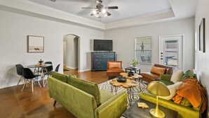 Ein geräumiges Wohnzimmer mit Essbereich, Deckenventilator und Fernseher im Hintergrund.