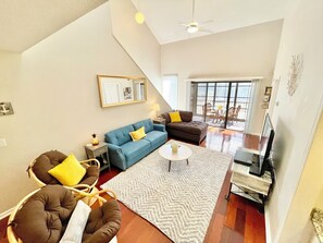 A spacious living area with a large sofa, a coffee table, and a TV. There is a balcony with a view. - Large Condo, 2 Floors, POOL Access, 1mile to beach (Myrtle Beach)