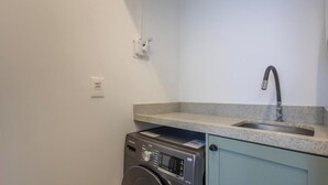 A compact kitchen with a washing machine, a sink, and a light switch on the wall. - Comfort and Convenience 350 Meters From the sea in Balneario Camboriu - Rlps (Balneário Camboriú)