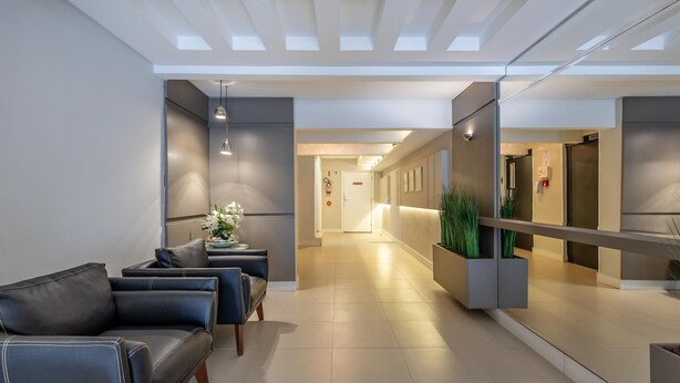 A modern lobby with a reception desk, seating area, and a hallway leading to other rooms. - Comfort and Convenience 350 Meters From the sea in Balneario Camboriu - Rlps (Balneário Camboriú)