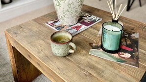 Ein Holztisch mit einer Tulpenvase, einer Kerze und einer Tasse.