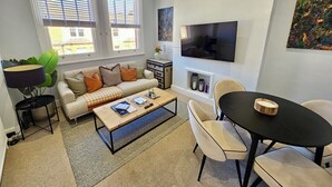 Ein modernes Wohnzimmer mit Sofa, Couchtisch, Fernseher und Kamin.