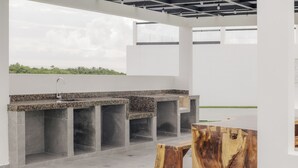 An outdoor kitchen area with a granite countertop, a sink, and built-in seating. - Emma Apartments New with Pool, Jacuzzi, close to the Beach, and playgrounds (Akumal)