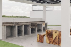 Eine Außenküche mit einer Granit Arbeitsplatte, einem Spülbecken und integrierten Sitzgelegenheiten.