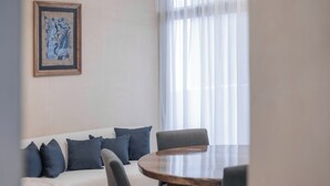 A room with a round wooden table, a white sofa with blue cushions, and a framed artwork on the wall. - Emma Apartments New with Pool, Jacuzzi, close to the Beach, and playgrounds (Akumal)