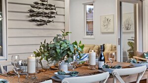 A dining table set with candles, wine glasses, and a centerpiece of green foliage. - Pet Friendly - Waves on Rye by Property Mums (Rye)