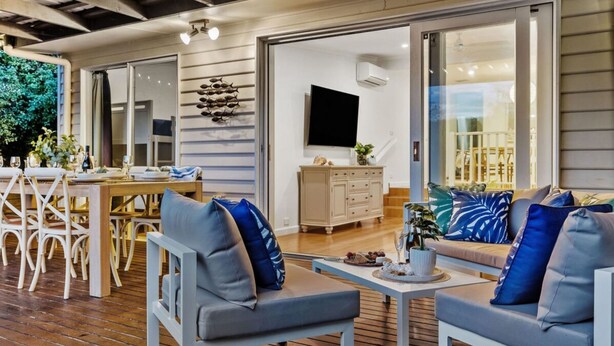 A modern outdoor living space with a dining area, seating, and a TV. - Pet Friendly - Waves on Rye by Property Mums (Rye)