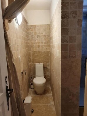 Un baño estrecho con paredes de baldosas color beige y un inodoro blanco.